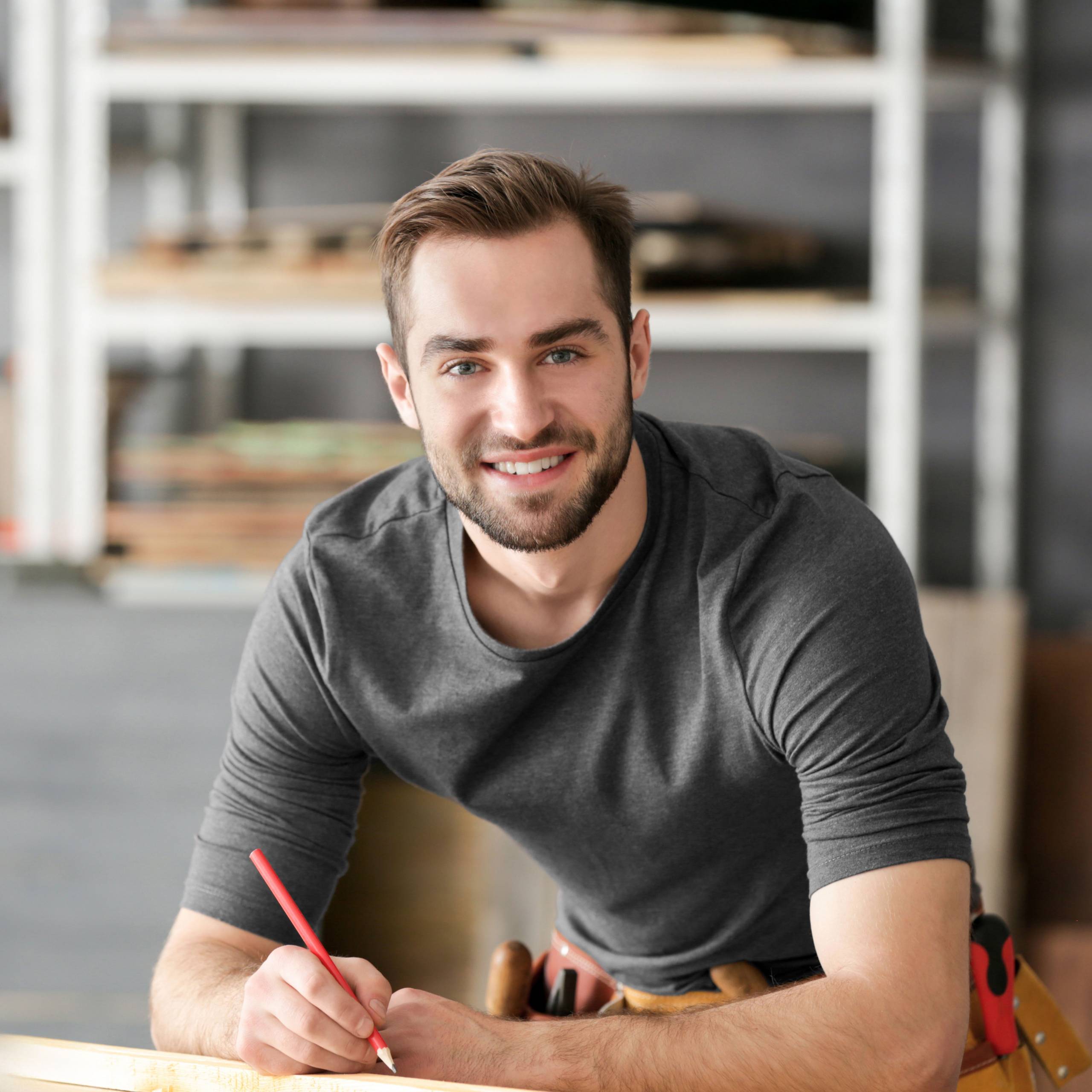 Menuisier accoudé a une planche de bois de face